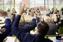 Abgeordnete im Plenarsaal mit gehobenen Händen während einer Abstimmung.